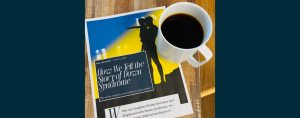 A printed article titled “How We Tell the Story of Down Syndrome” by Amy Julia Becker lies on a wooden table beside a white mug of black coffee. The article features a silhouette of an adult holding a child against a blue and yellow background and includes the subtitle, “The words, statistics, and stories we share matter.”