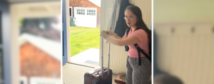 Penny who has Down syndrome gets ready to leave the house through the open front door, pushing her suitcase in front of her
