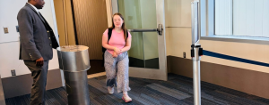 Penny, our daughter who has Down syndrome, walks out of a jet bridge after getting off a plane while a uniformed airline staff member stands nearby.