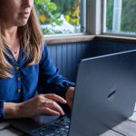 Amy Julia sits at a table typing on her laptop