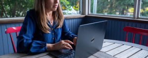 Amy Julia sits at a table typing on her laptop