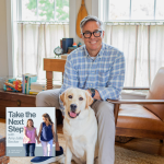 David Thomas in a blue plaid shirt sits on a chair indoors with a white-and-tan dog sitting on the floor; a living room with windows, chairs, and bookshelves is in the background. Near the middle bottom is a smaller image of the podcast cover where Penny and Amy Julia walk hand in hand, with Amy Julia looking toward Penny.