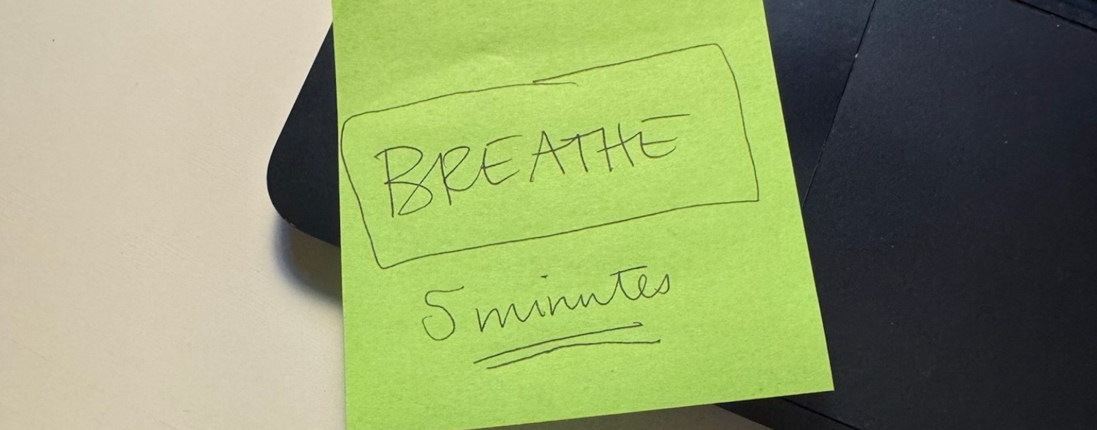 a green sticky note is on a laptop with the words "breathe" and "five minutes"