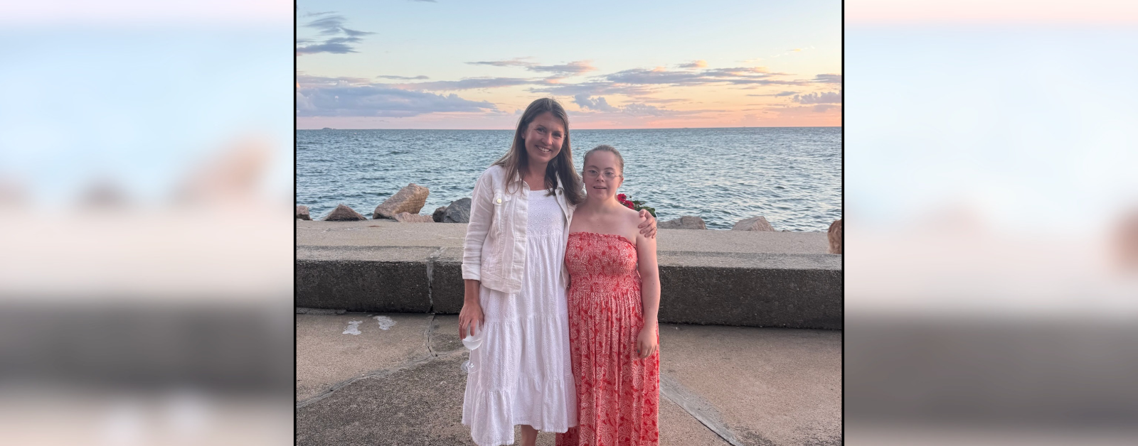 I'm standing with Penny on a pier with a beautiful sunset and ocean behind us