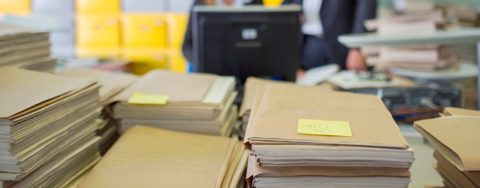 Stacks of brown file folders and papers on a desk in an office