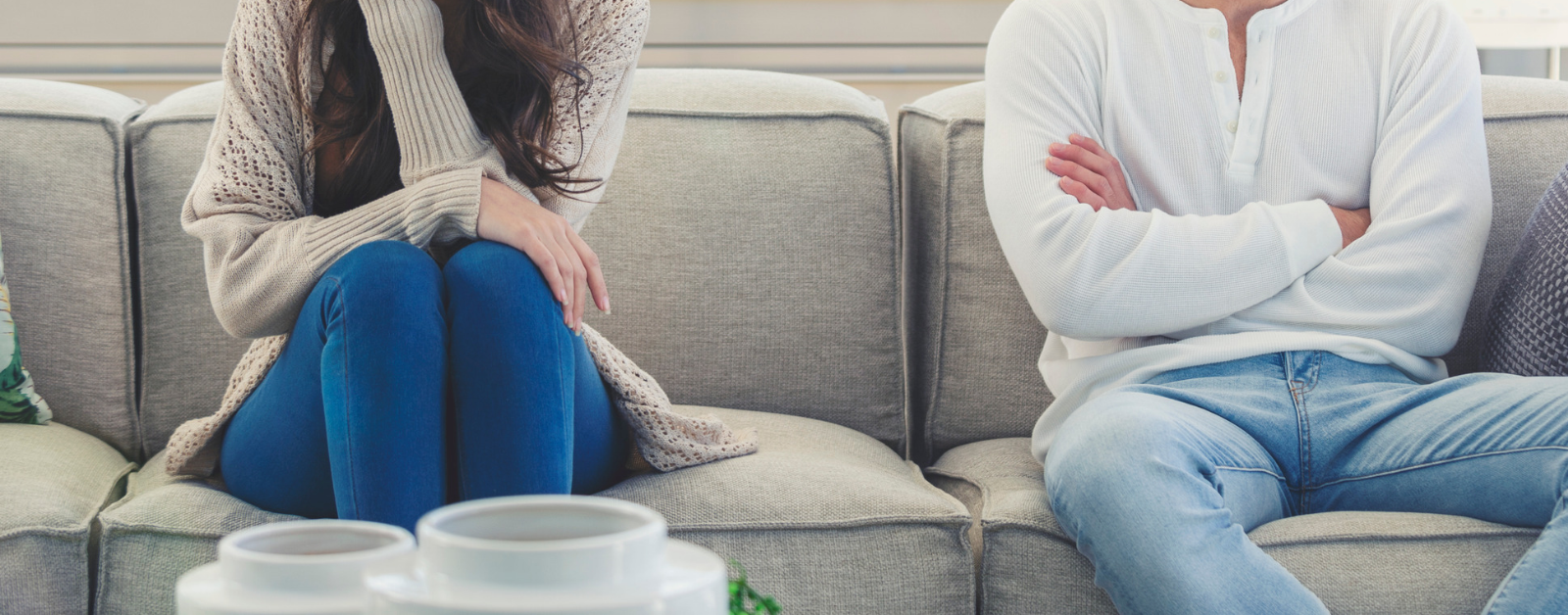 couple sits far apart on a couch facing away from each other