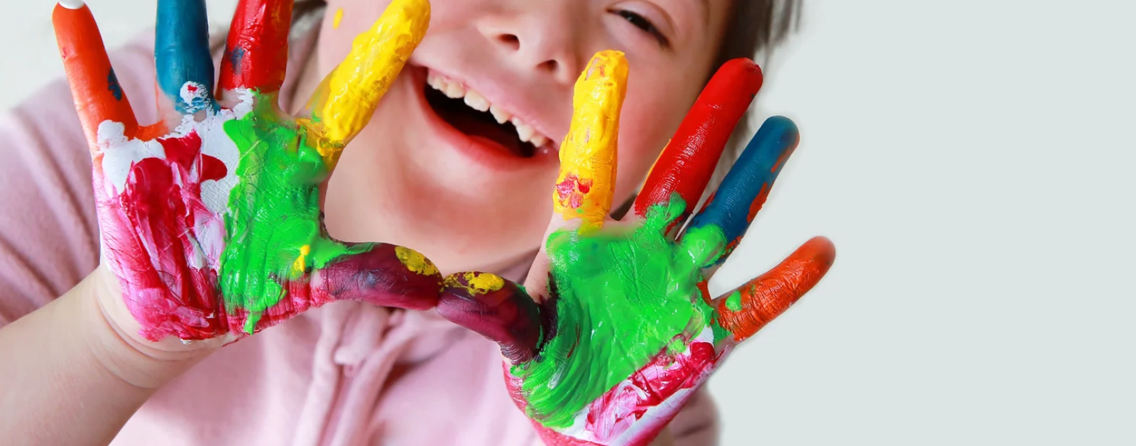 a young girl with Down syndrome holds up her brightly painted hands