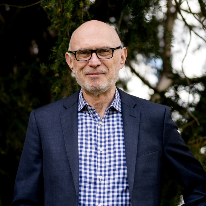 AJB-featured season 8 Miroslav Volf dark blue graphic with geometric shape overlays and the Reimagining the Good Life with Amy Julia Becker podcast logo in bottom right corner. In the middle of the graphic is a photo of Miroslav Volf, PhD