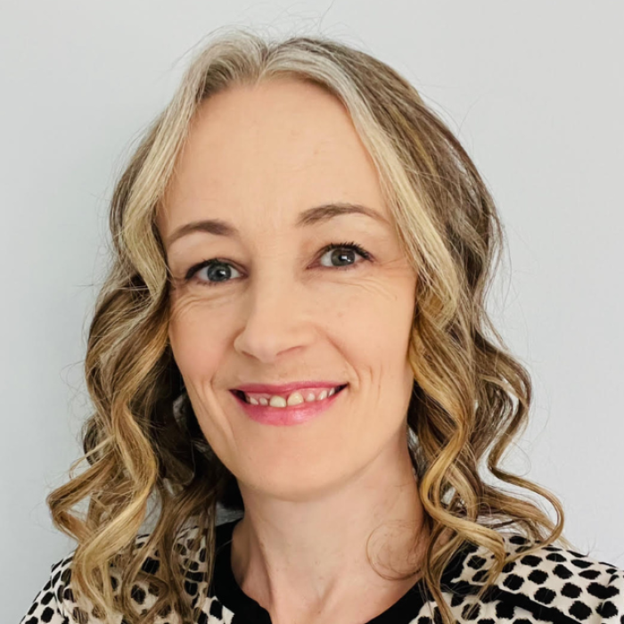 AJB-featured season 8 carrie hahn dark blue graphic with geometric shape overlays and the Reimagining the Good Life with Amy Julia Becker podcast logo in bottom right corner. In the middle of the graphic is a photo of Carrie Hahn