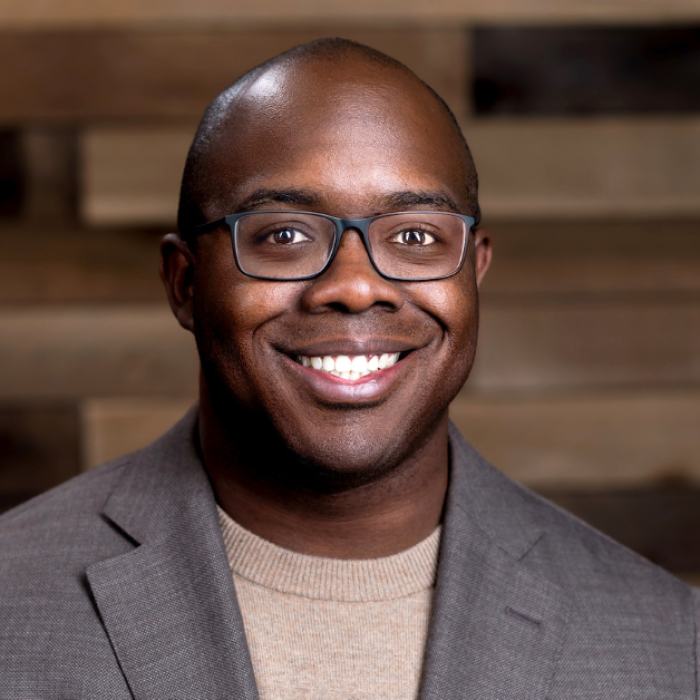 AJB-featured season 8 esau mccaulley dark blue graphic with geometric shape overlays and the Reimagining the Good Life with Amy Julia Becker podcast logo in bottom right corner. In the middle of the graphic is a photo of Esau McCaulley