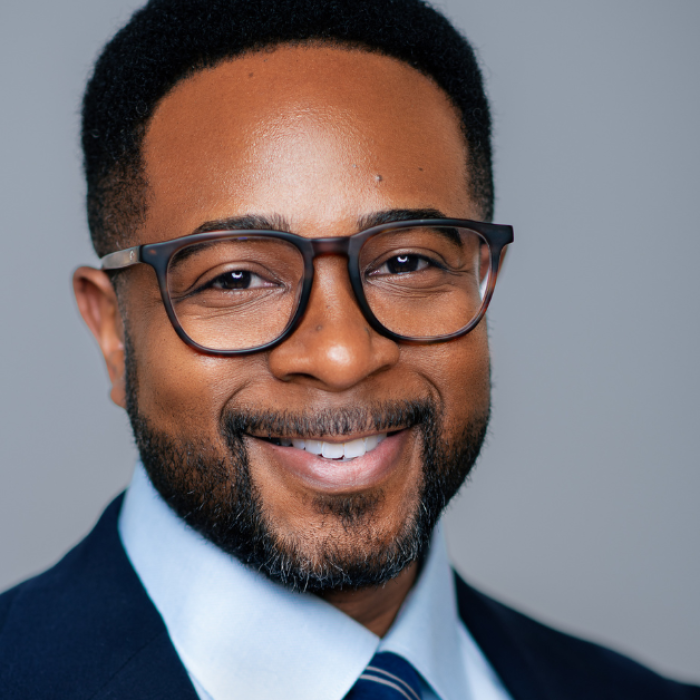 AJB-featured season 8(1560 × 628 px) jemar tisby dark blue graphic with geometric shape overlays and the Reimagining the Good Life with Amy Julia Becker podcast logo in bottom right corner. In the middle of the graphic is a photo of Jemar Tisby